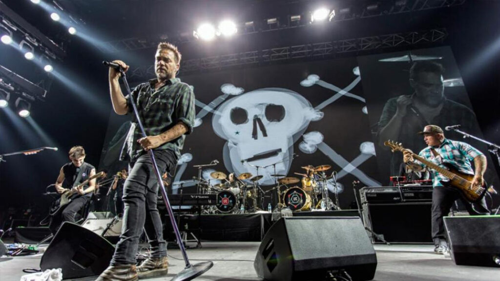 Integrantes de Los Fabulosos Cadillacs en concierto, con una impresionante escenografía de calavera de fondo