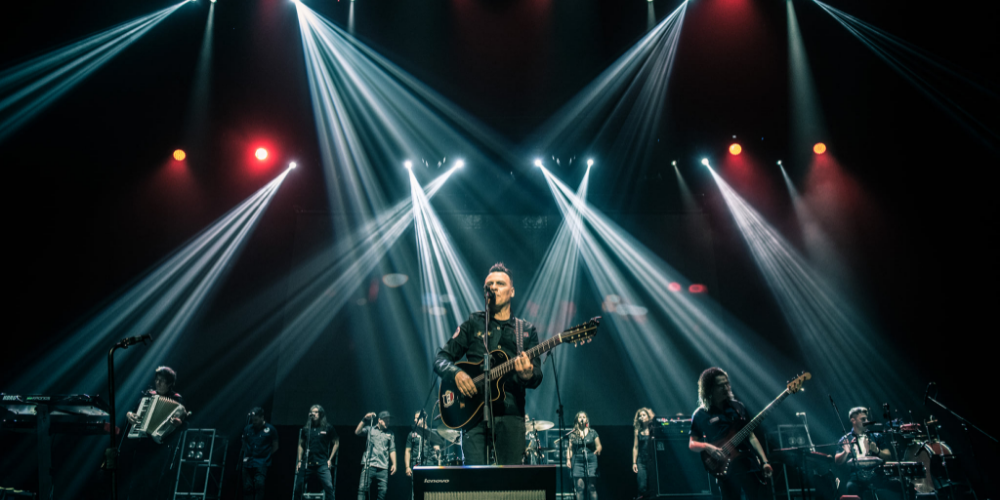 Tabaré Cardozo en concierto, vestido de negro y cantando con su guitarra y su banda en el escenario