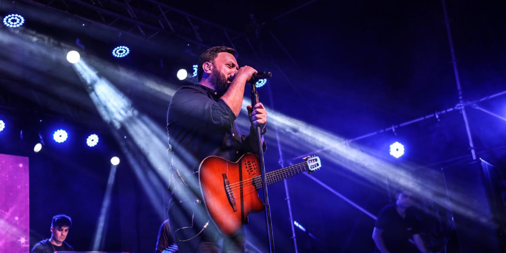 Lucas Sugo interpretando emocionadamente sus canciones sobre el escenario, bajo las luces del concierto