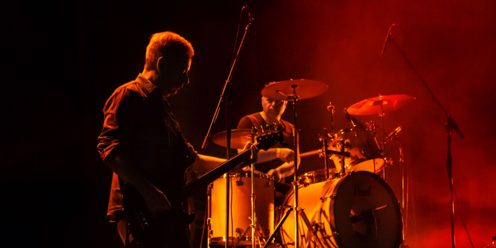 Dos miembros de La Foca tocando bajo una intensa luz roja en concierto