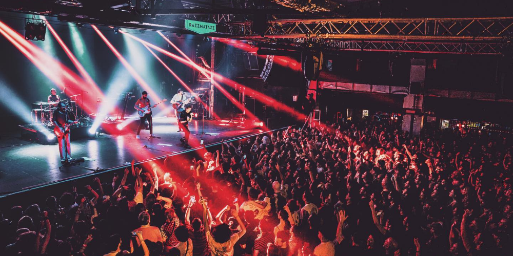 Cuarteto de Nos actuando en el escenario del Antel Arena con una multitud de fanáticos emocionados