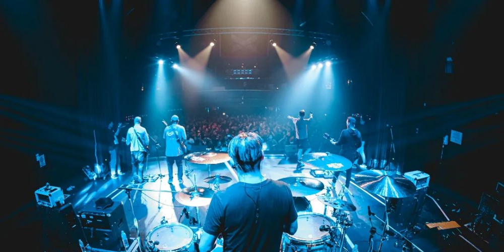 Vista desde el escenario de Eterna Inocencia tocando, con la banda en primer plano y el público entusiasmado de fondo