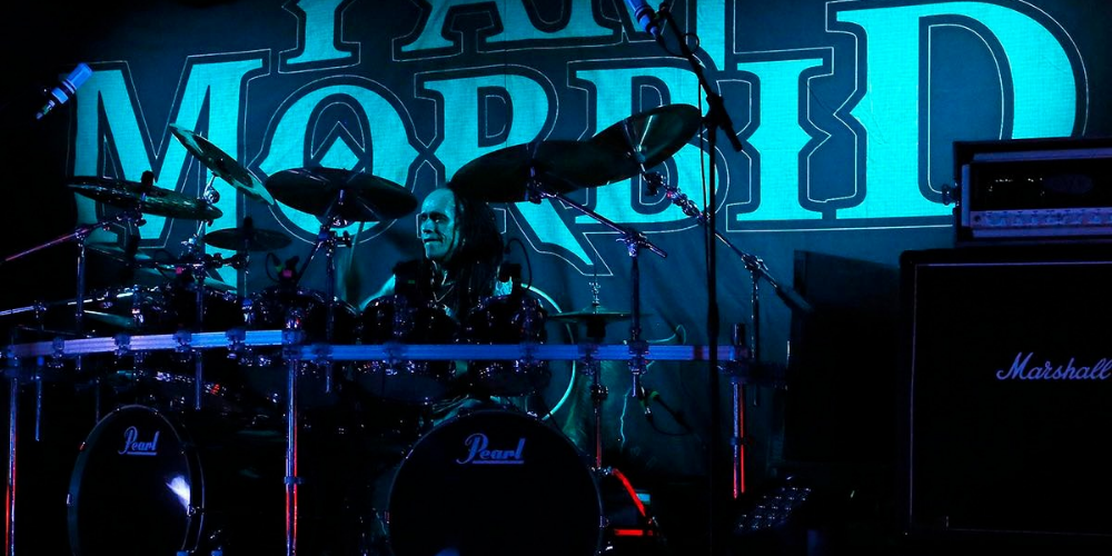 Baterista de I Am Morbid tocando su set de batería bajo una iluminación azul intensa