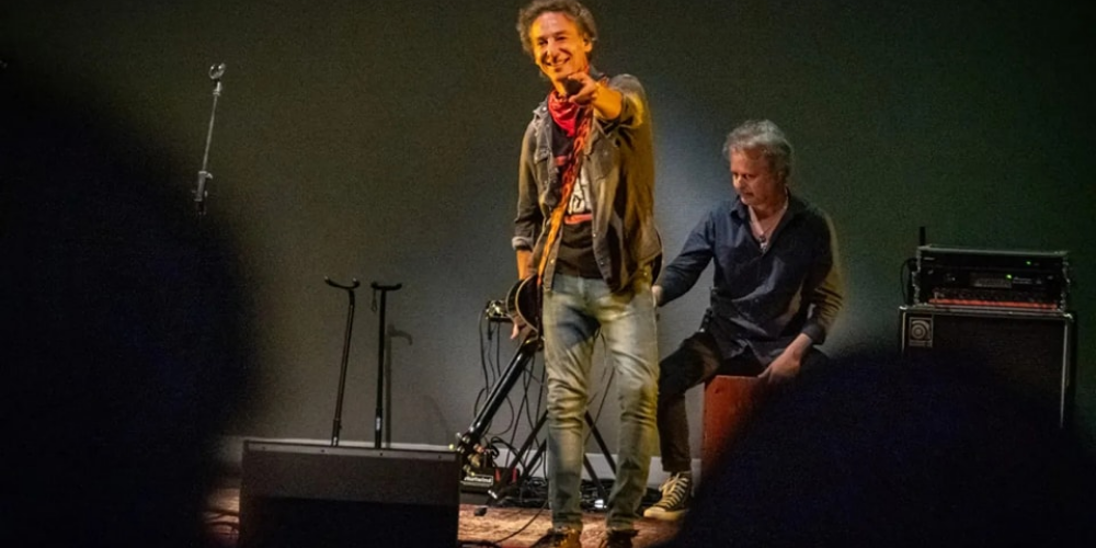 Javier Calamaro sonriendo y apuntando hacia el público con su micrófono durante un concierto