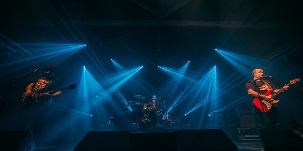 Integrantes de La Triple Nelson tocando en vivo bajo luces azules