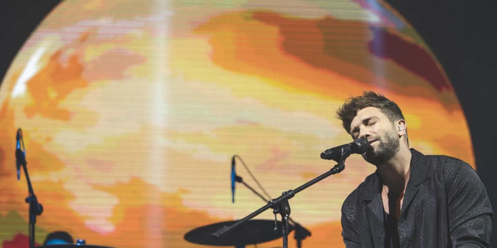 Pablo Alborán vestido de negro cantando emotivamente con los ojos cerrados